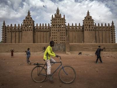 En gutt sykler forbi "the Great Mosque of Djenné", som sammen med gamlebyen i Djenné, har vært på Verdensarvlisten siden 1988. UN Photo/Marco Dormino